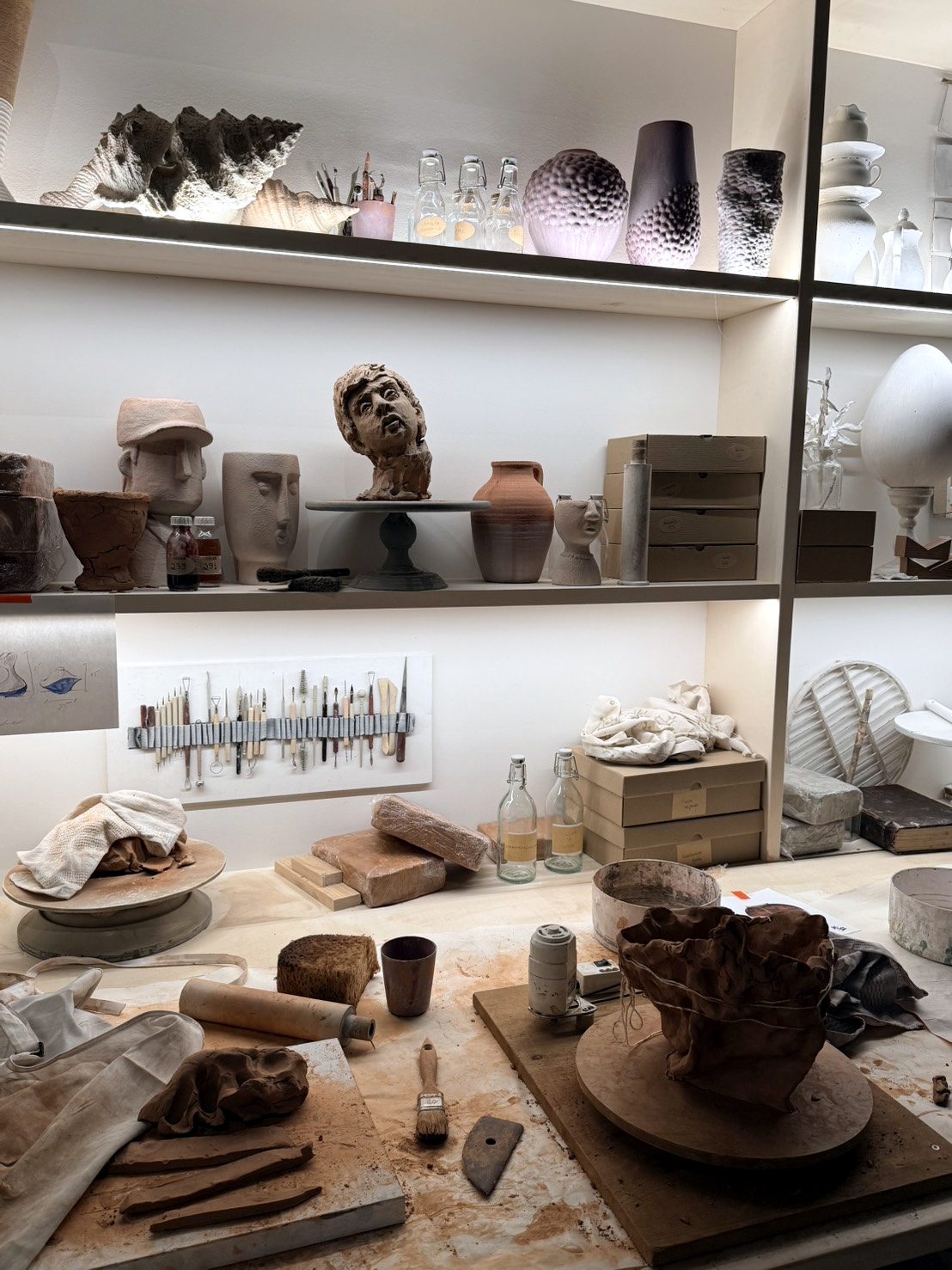Ceramic workshop with clay, tools and vessels on shelves